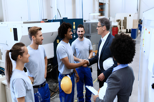 Dono de indústria e sua equipe felizes com a ótima gestão industrial, que foi possível graças às vantagens de um ERP Industrial.