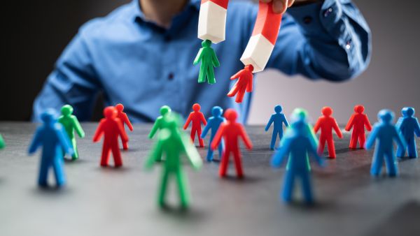 Homem usando imã para pegar  bonecos de diferentes cores representando classificação de potenciais clientes na gestão de leads