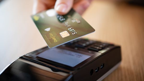 Consumidor fazendo pagamento por aproximação com cartão em máquina conectada ao tef