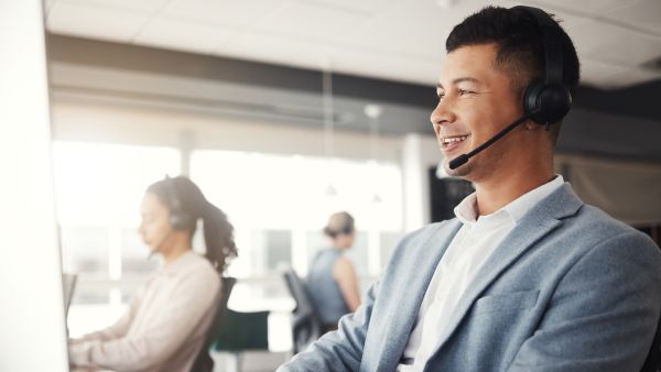 Atendente satisfeito com resultado de interações com clientes após acessar ERP para e-commerce