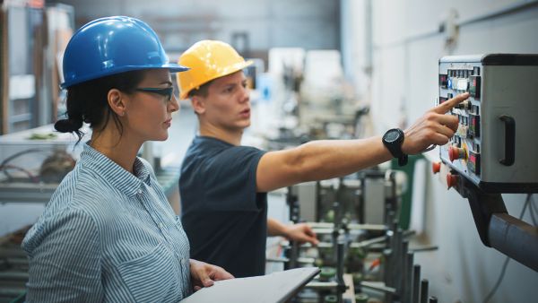 Líder de fábrica acompanhando desempenho de máquina ao lado de colaborador