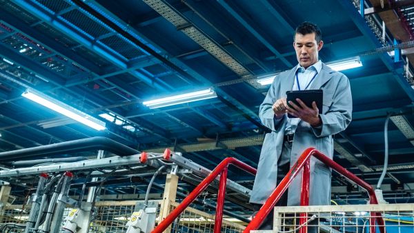 Líder monitorando desempenho das atividades no ERP enquanto observa trabalho na fábrica