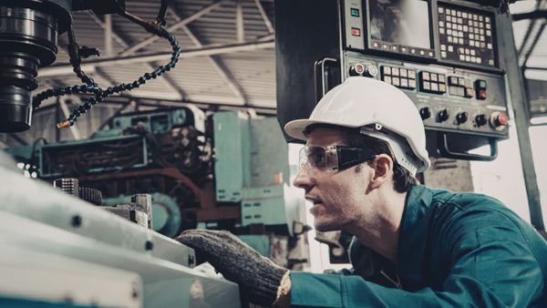 Colaborador de indústria operando máquina na confecção de produtos seguindo o programa no plano mestre de produção